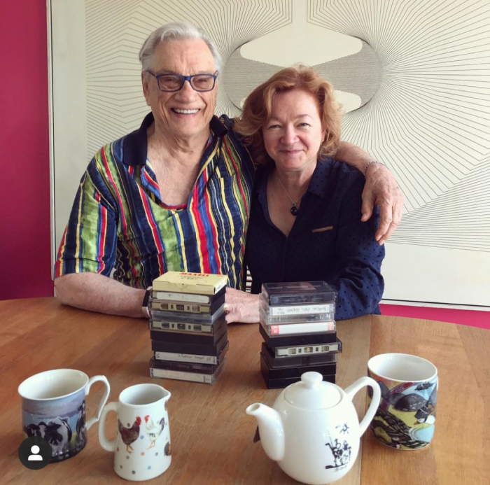 George Bowering and Jean Baird sit at their kitchen table with cassette tapes and tea pots in front of them.