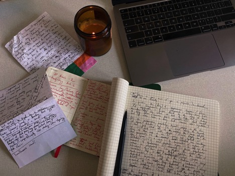 Image of note books and a candle in a jar and the corner of a laptop keyboard form above.