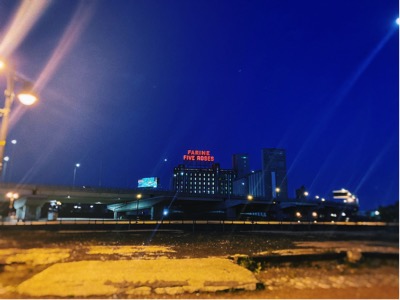Image of the factory with glowing red letters on top of building reading Farine Five Roses at night.
