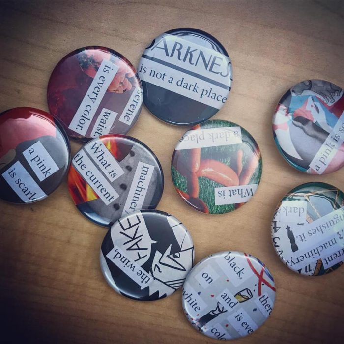 A selection of the buttons made in the workshop. The buttons read "Darkness is not a dark place", "serene waist is every colour," "a pink is scarlet," "what is a dark place," "what is the current machinery," "black on white and there is every colour," "the wind, FAKE" and finally "the current machinery distinguishes it dark".